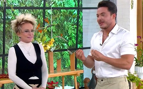 Ana Maria Braga de óculos de grau, blusa branca e preta, ao lado de Wesley Safadão, de camisa branca e calça bege