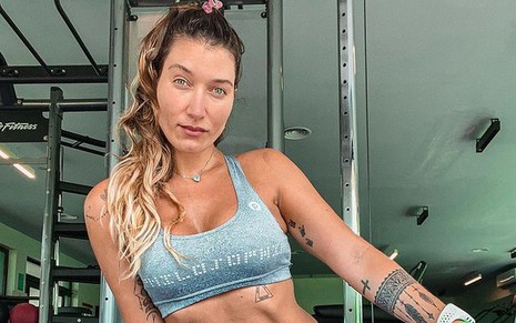 Gabriela Pugliesi de cabelo preso, top cinza e short curtinho combinando na academia