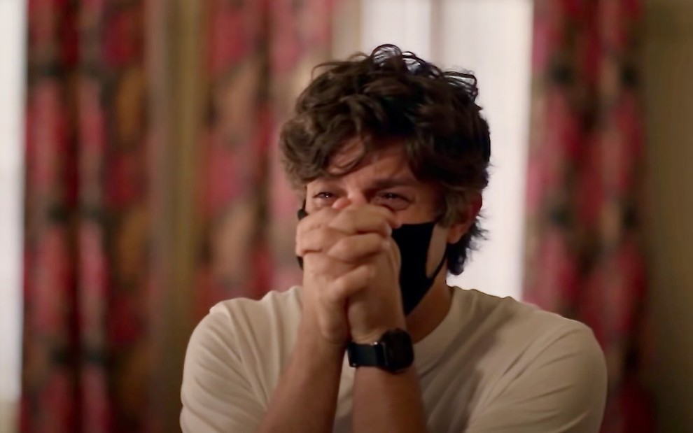 O ator Chay Suede usa máscara preta e coloca as mãos nem cima ao chorar em cena de Amor de Mãe