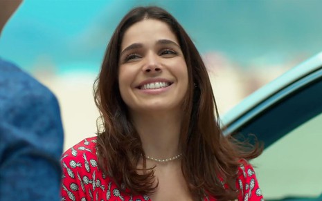 Sabrina Petraglia em cena de Haja Coração: caracterizada como Shirlei, personagem sorri para alguém fora do quadro