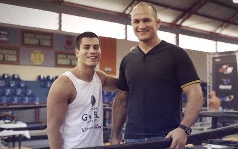 Arthur Aguiar está à esquerda ao lado de Junior Cigano no cenário da Academia de Gael em Malhação Sonhos