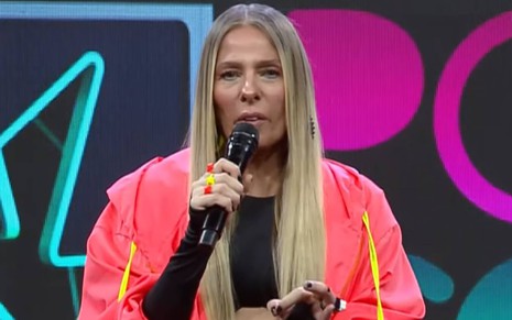 Foto de Adriane Galisteu; ela veste jaqueta rosa e camiseta preta