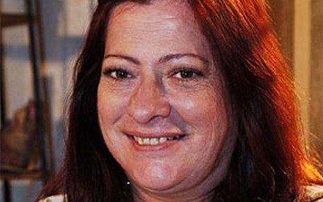 A atriz Lucy Mafra como Claudete em América; ela está olhando para a frente e sorrindo para a foto
