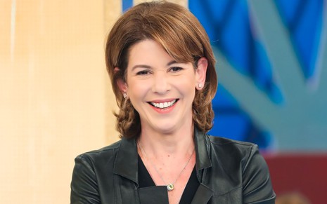 Daniela Beyruti durante gravação do especial dos 60 anos do Programa Silvio Santos; sorridente, ela veste jaqueta de couro preta