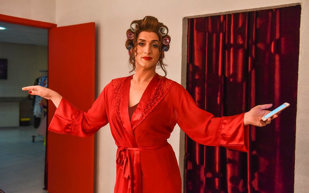 Paulo Gustavo como Dona Hermínia de vestido vermelho e braços abertos