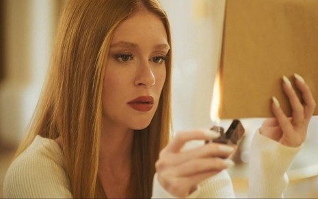 Marina Ruy Barbosa coloca fogo em um envelope em cena da novela Fuzuê como a vilã Preciosa