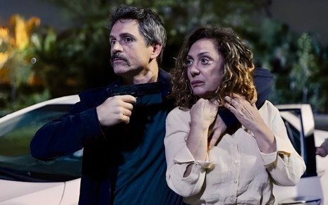 Felipe Rocha com arma apontada para Eliane Giardini em cena de sequestro de Terra e Paixão na qual eles estão como Gregório e Agatha