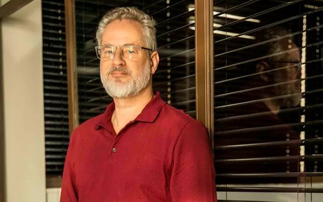 O ator Dan Stulbach como Ibraim em Pantanal; de óculo, ele está olhando para a frente, com cara séria
