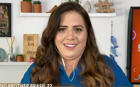 Tati Machado no Encontro desta segunda-feira (17). Ela veste uma camisa azul e está sorrindo para a câmera e usando fones de ouvido.