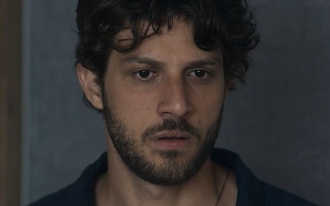 O ator Chay Suede como Ari em Travessia; ele está olhando para baixo com cara de preocuipado