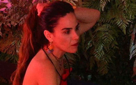 Wanessa Camarga está sentada no chão da área externa do BBB 24; ela segura os cabelos e parece tensa