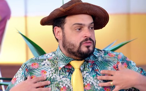 Matheus Ceará está sentado no banco do programa A Praça É Nossa