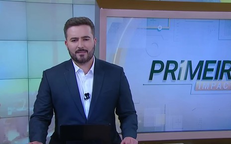 Felipe Malta tem expressão séria na frente de telão do Primeiro Impacto, do SBT