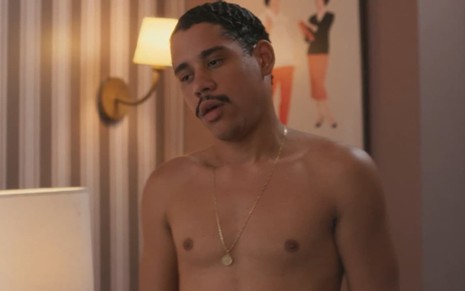 O ator Cauê Campos sério, sem camisa, em cena de Garota do Momento