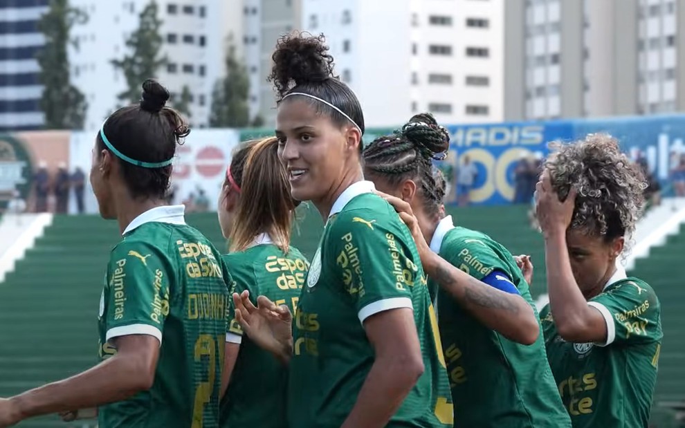 Jogadoras do Palmeiras se abraçam em campo de futebol